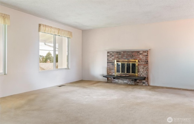 unfurnished living room with carpet floors, a textured ceiling, and a fireplace