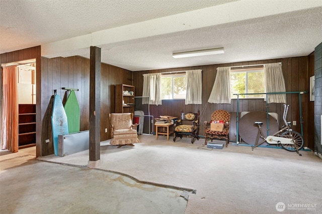 sitting room featuring wood walls, a textured ceiling, and carpet floors