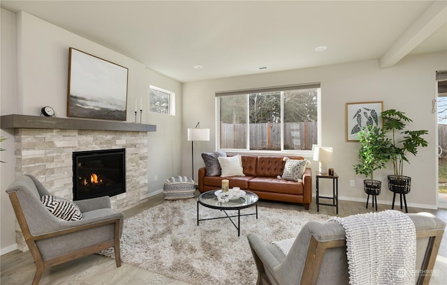 living room with beamed ceiling, a fireplace, and light hardwood / wood-style flooring