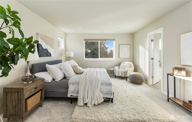 bedroom featuring light colored carpet and ensuite bath