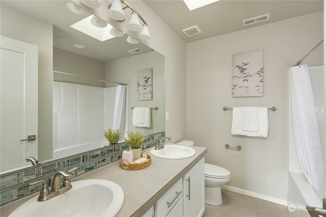 full bathroom with toilet, a skylight, vanity, tile patterned flooring, and backsplash