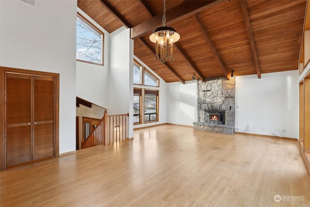 unfurnished living room featuring a stone fireplace, an inviting chandelier, high vaulted ceiling, wood ceiling, and beam ceiling