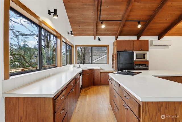 kitchen with vaulted ceiling with beams, wood ceiling, a wall mounted air conditioner, light hardwood / wood-style flooring, and black appliances