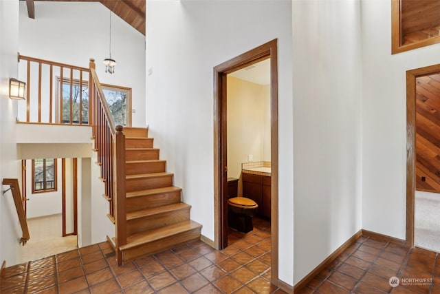 staircase featuring tile patterned flooring, high vaulted ceiling, wooden ceiling, and a chandelier