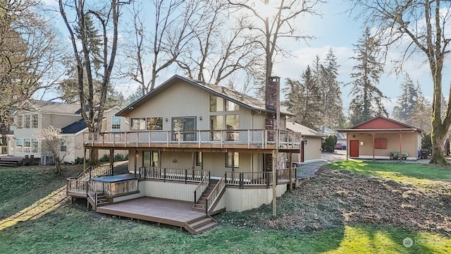 rear view of house with a wooden deck, a lawn, and a hot tub