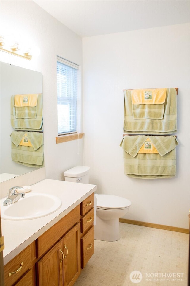 bathroom with vanity, toilet, and baseboards