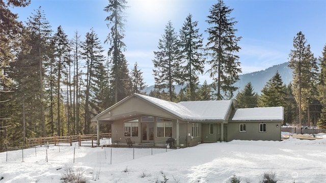 snow covered back of property featuring a mountain view