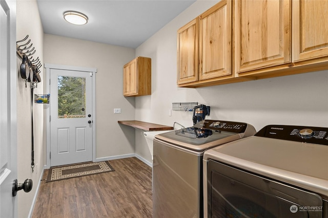 laundry room with washing machine and clothes dryer, dark wood-type flooring, and cabinets