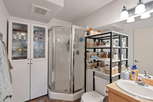 bathroom featuring vanity, toilet, and an enclosed shower