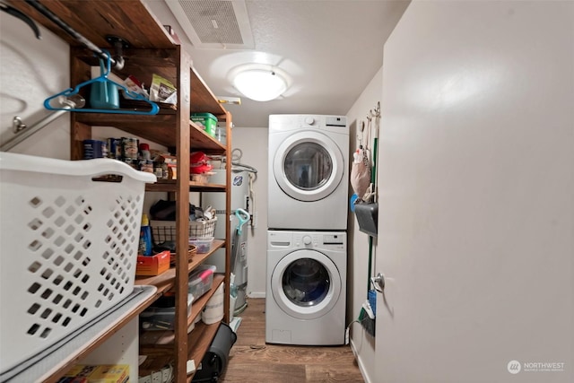 clothes washing area featuring stacked washer / drying machine, light hardwood / wood-style flooring, and secured water heater