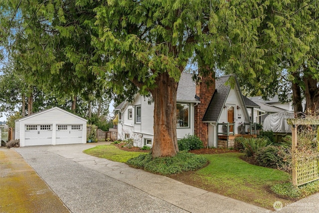 view of front of house featuring an outbuilding, a front yard, a garage, and a shingled roof