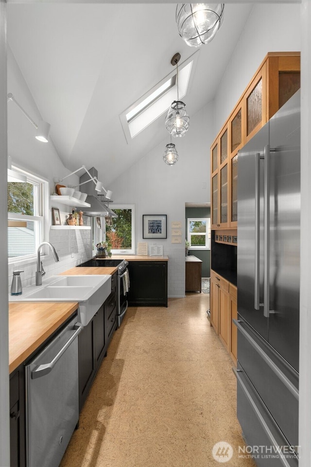 kitchen with open shelves, a wealth of natural light, appliances with stainless steel finishes, and a sink