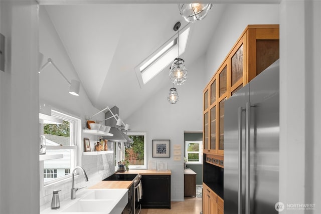 kitchen featuring open shelves, a skylight, a sink, decorative backsplash, and stainless steel appliances