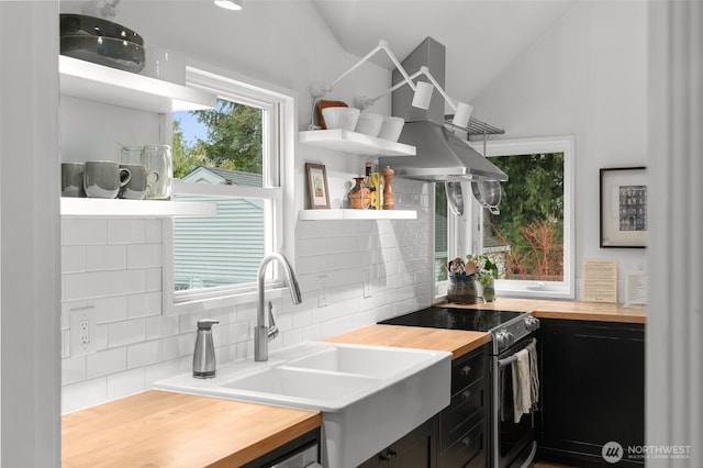 kitchen with wooden counters, electric range oven, dark cabinetry, exhaust hood, and open shelves