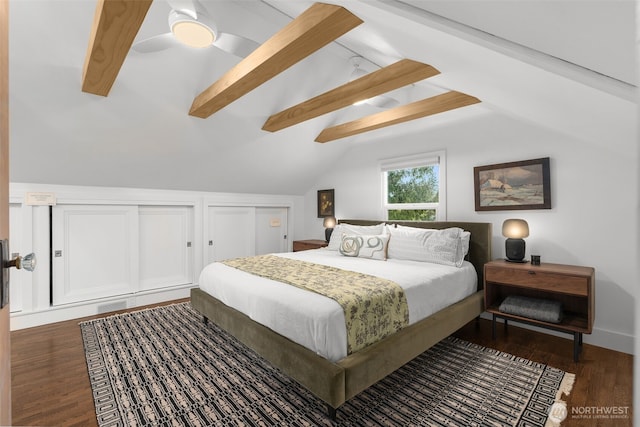 bedroom featuring two closets, lofted ceiling with beams, ceiling fan, and wood finished floors