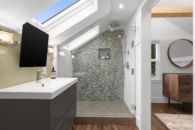 bathroom featuring vanity, lofted ceiling with skylight, wood finished floors, and a shower stall