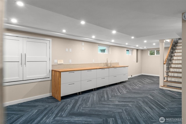 kitchen with recessed lighting, white cabinetry, baseboards, and a sink