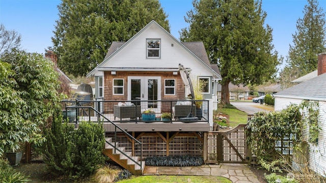 rear view of property featuring a shingled roof, a wooden deck, stairs, french doors, and a gate