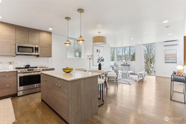 kitchen featuring backsplash, hardwood / wood-style flooring, hanging light fixtures, and stainless steel appliances