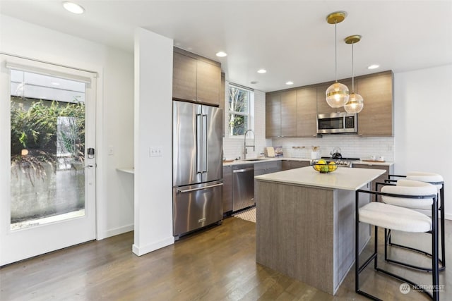 kitchen featuring pendant lighting, a kitchen island, a kitchen bar, stainless steel appliances, and sink