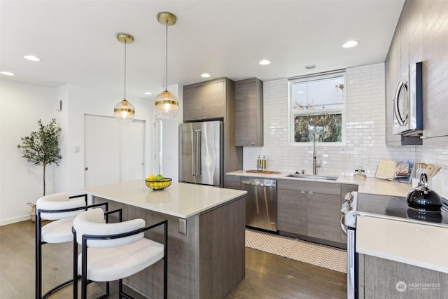 kitchen featuring decorative light fixtures, sink, tasteful backsplash, a kitchen island, and stainless steel appliances