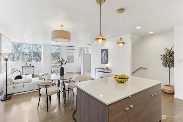 kitchen with a wall unit AC, pendant lighting, a center island, and dark brown cabinets