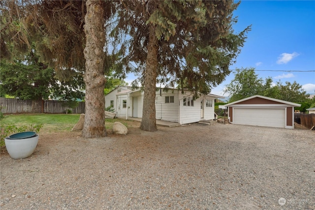 single story home featuring a garage, a front lawn, and an outdoor structure