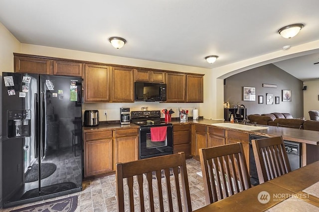 kitchen featuring sink, vaulted ceiling, black appliances, and kitchen peninsula