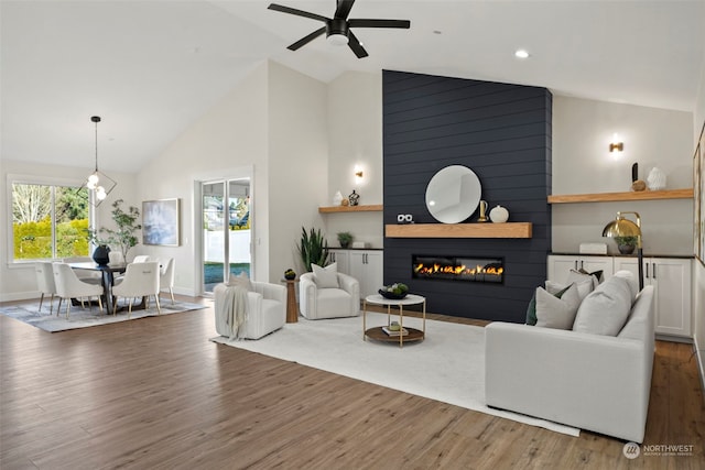 living room with high vaulted ceiling, a large fireplace, dark hardwood / wood-style floors, and ceiling fan