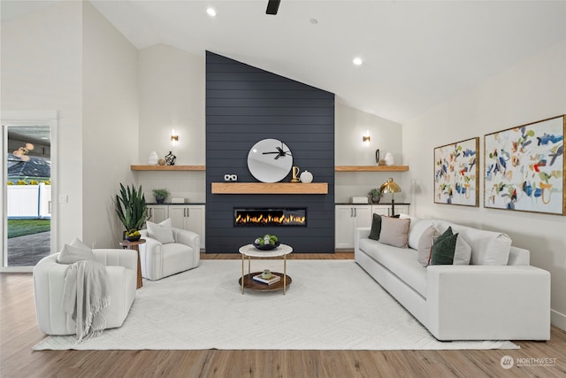 living room featuring a fireplace, light hardwood / wood-style flooring, high vaulted ceiling, and ceiling fan