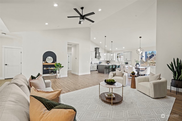 living room with light hardwood / wood-style flooring, vaulted ceiling, and ceiling fan