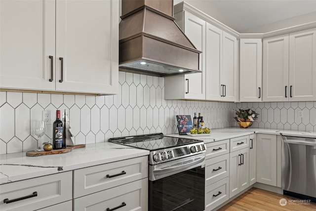 kitchen with backsplash, white cabinetry, custom range hood, and stainless steel appliances