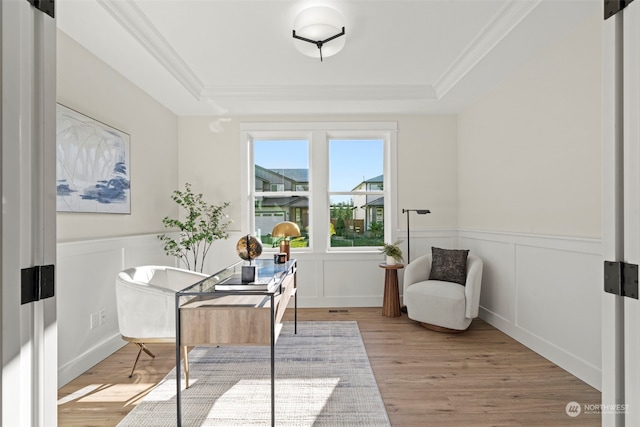 sitting room featuring crown molding, light hardwood / wood-style flooring, and a raised ceiling