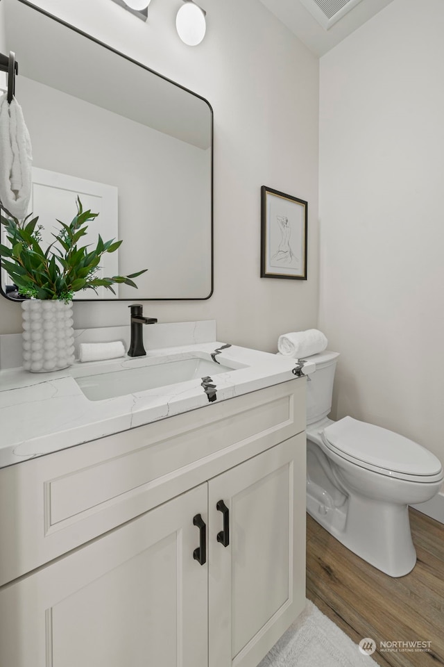 bathroom with hardwood / wood-style flooring, toilet, and vanity