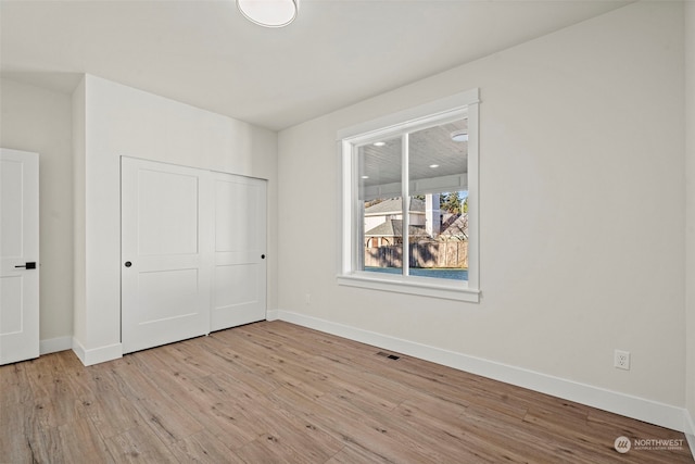 unfurnished bedroom with light wood-type flooring and a closet