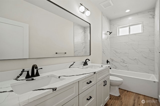 full bathroom with wood-type flooring, toilet, tiled shower / bath, and vanity