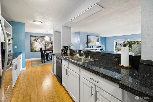 kitchen with decorative light fixtures, sink, white cabinets, black dishwasher, and light hardwood / wood-style floors