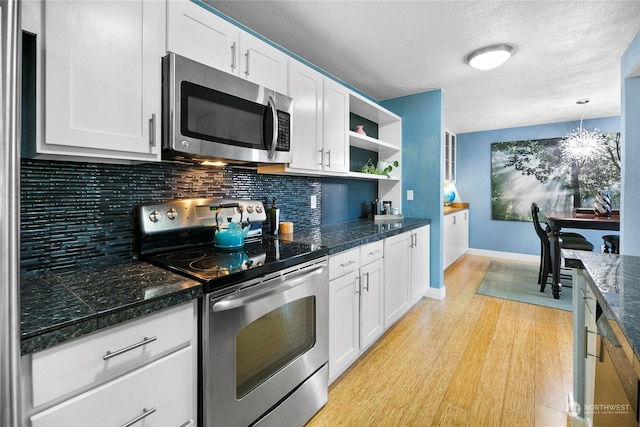 kitchen featuring decorative light fixtures, white cabinets, tasteful backsplash, and appliances with stainless steel finishes