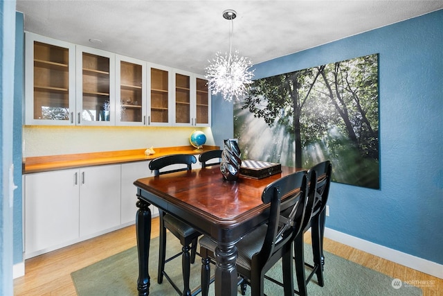 dining area with light wood-type flooring and an inviting chandelier