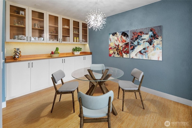 dining area with a chandelier, light wood finished floors, and baseboards