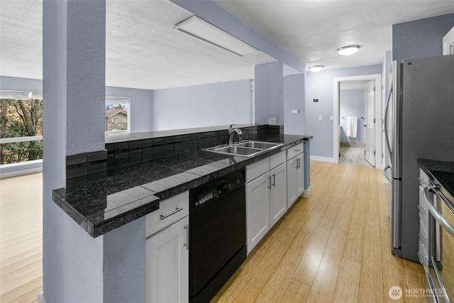 kitchen with baseboards, stainless steel appliances, light wood-style floors, white cabinetry, and a sink