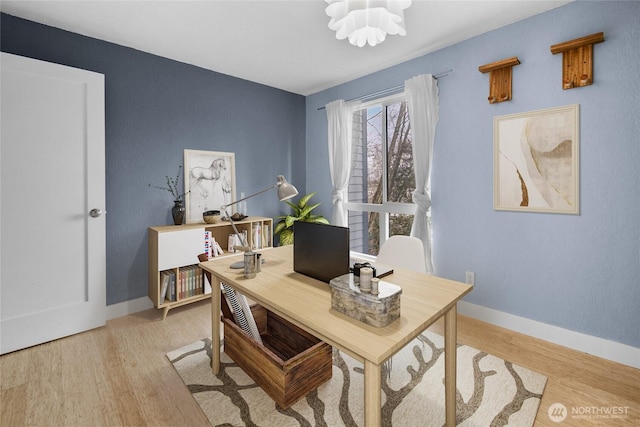 office area featuring light wood-type flooring, baseboards, and an inviting chandelier