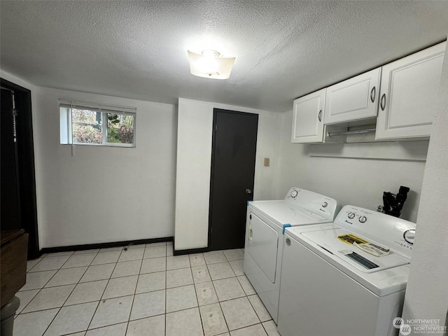 clothes washing area with cabinets, a textured ceiling, and independent washer and dryer