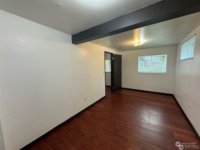 unfurnished room with beamed ceiling, dark hardwood / wood-style floors, and a textured ceiling