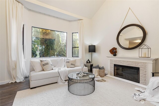 living room featuring vaulted ceiling, dark hardwood / wood-style floors, and a fireplace