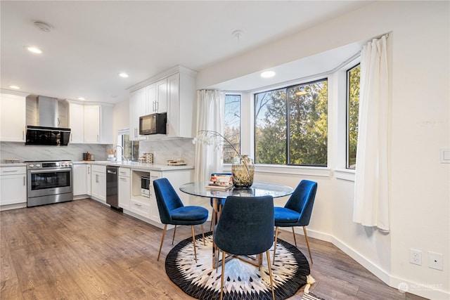 kitchen featuring hardwood / wood-style floors, backsplash, white cabinetry, and stainless steel appliances