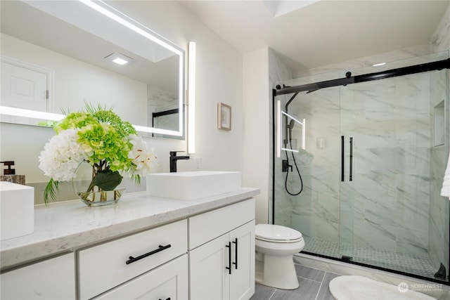 bathroom featuring vanity, toilet, a shower with shower door, and tile patterned flooring