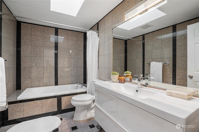 full bathroom featuring vanity, a skylight, tile walls, toilet, and shower / tub combo with curtain