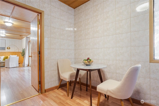 dining room featuring wood-type flooring and tile walls