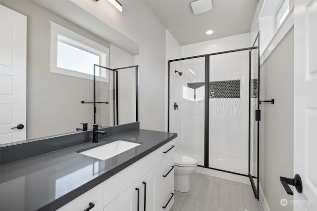 bathroom with a shower with shower door, toilet, and vanity